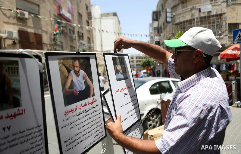 Palestinians walk past posters hanging for martyrs to show solidarity with them, in the West Bank city of Ramallah on June 13, 2016. Photo by Shadi Hatem