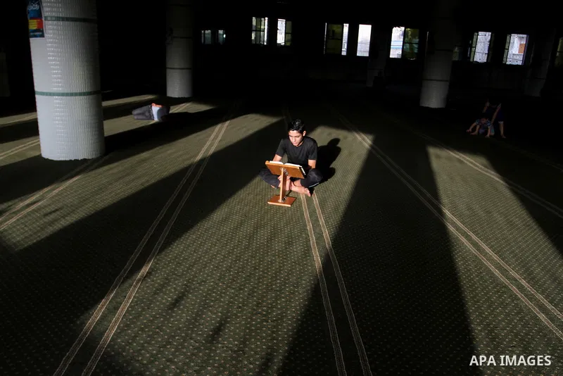 A Palestinian man sits reading the Koran, Islam's holy book, at the mosque during the Muslim fasting month of Ramadan, in Rafah in the southern Gaza strip on June 13, 2016. Photo by Abed Rahim Khatib