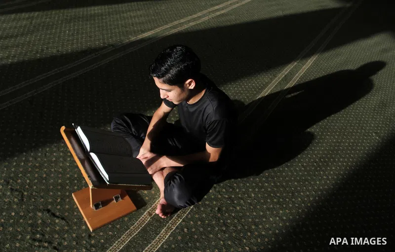A Palestinian man sits reading the Koran, Islam's holy book, at the mosque during the Muslim fasting month of Ramadan, in Rafah in the southern Gaza strip on June 13, 2016. Photo by Abed Rahim Khatib