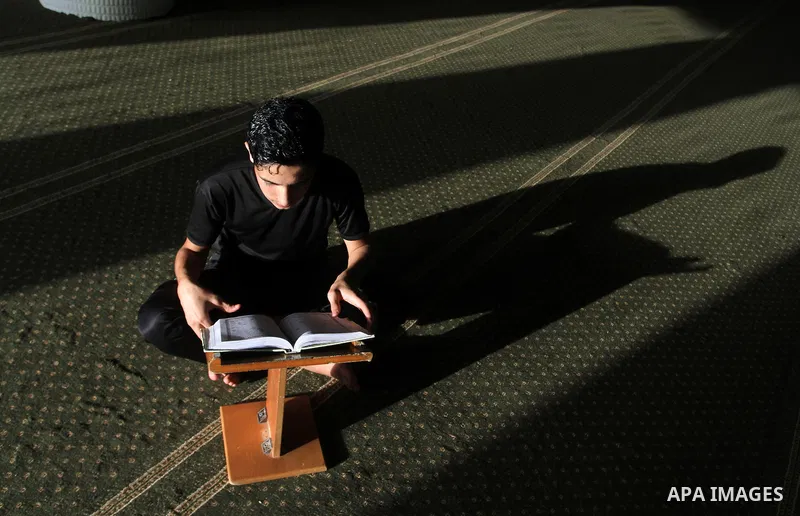 A Palestinian man sits reading the Koran, Islam's holy book, at the mosque during the Muslim fasting month of Ramadan, in Rafah in the southern Gaza strip on June 13, 2016. Photo by Abed Rahim Khatib