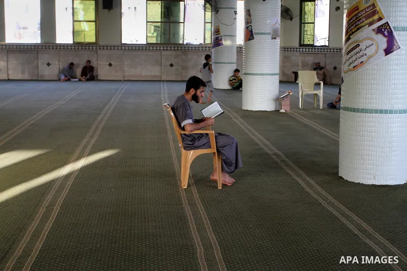 A Palestinian man sits reading the Koran, Islam's holy book, at the mosque during the Muslim fasting month of Ramadan, in Rafah in the southern Gaza strip on June 13, 2016. Photo by Abed Rahim Khatib