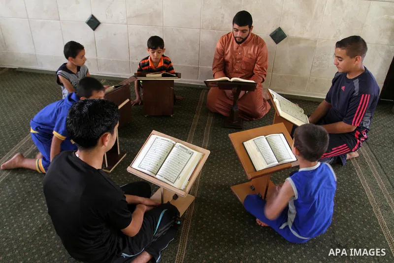 Palestinian men sit reading the Koran, Islam's holy book, at the mosque during the Muslim fasting month of Ramadan, in Rafah in the southern Gaza strip on June 13, 2016. Photo by Abed Rahim Khatib