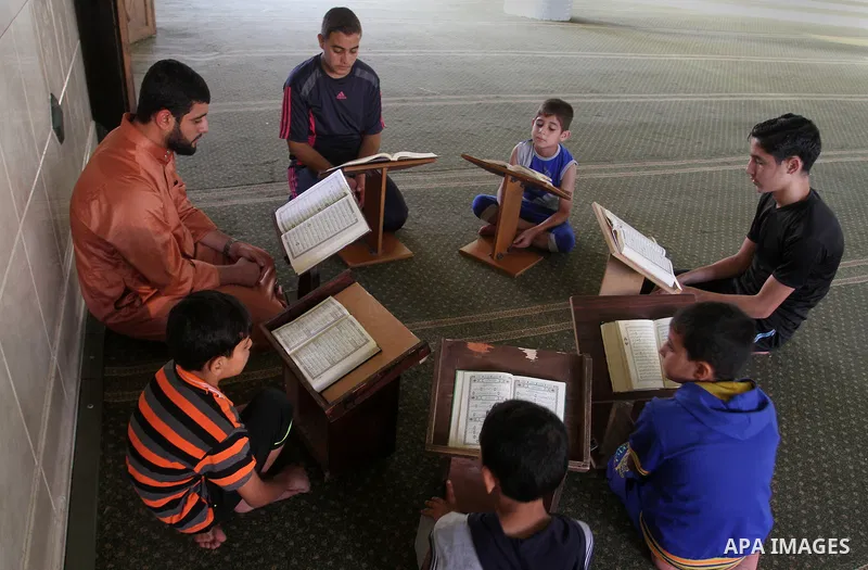 Palestinian men sit reading the Koran, Islam's holy book, at the mosque during the Muslim fasting month of Ramadan, in Rafah in the southern Gaza strip on June 13, 2016. Photo by Abed Rahim Khatib