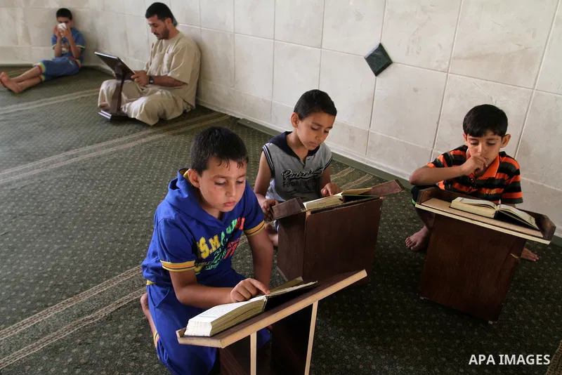 Palestinian men sit reading the Koran, Islam's holy book, at the mosque during the Muslim fasting month of Ramadan, in Rafah in the southern Gaza strip on June 13, 2016. Photo by Abed Rahim Khatib