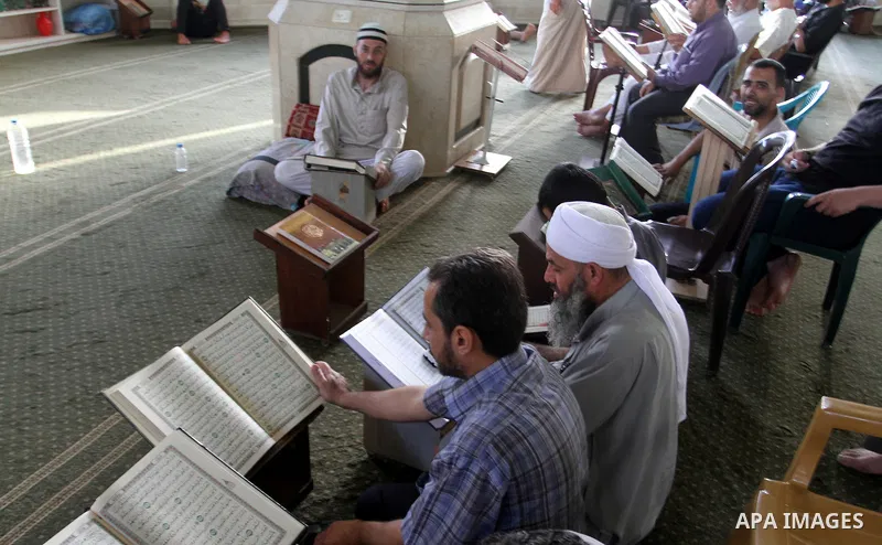 Palestinian men sit reading the Koran, Islam's holy book, at the mosque during the Muslim fasting month of Ramadan, in Rafah in the southern Gaza strip on June 13, 2016. Photo by Abed Rahim Khatib