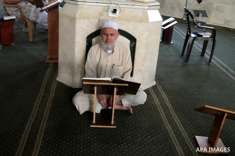 A Palestinian man sits reading the Koran, Islam's holy book, at the mosque during the Muslim fasting month of Ramadan, in Rafah in the southern Gaza strip on June 13, 2016. Photo by Abed Rahim Khatib
