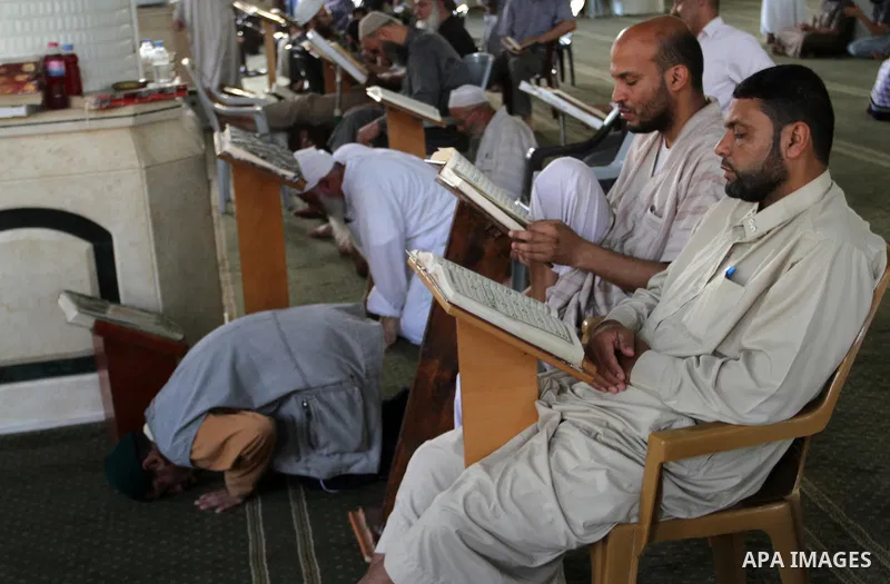 Palestinian men sit reading the Koran, Islam's holy book, at the mosque during the Muslim fasting month of Ramadan, in Rafah in the southern Gaza strip on June 13, 2016. Photo by Abed Rahim Khatib