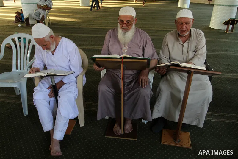 Palestinian men sit reading the Koran, Islam's holy book, at the mosque during the Muslim fasting month of Ramadan, in Rafah in the southern Gaza strip on June 13, 2016. Photo by Abed Rahim Khatib