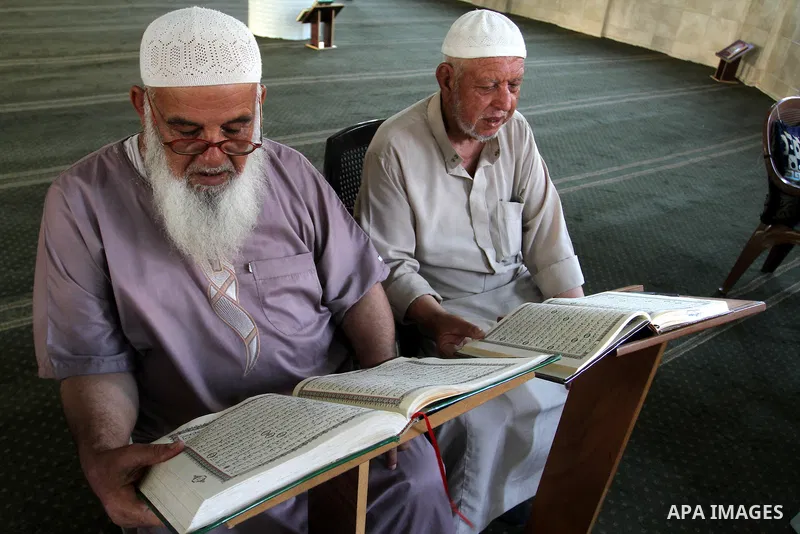 Palestinian men sit reading the Koran, Islam's holy book, at the mosque during the Muslim fasting month of Ramadan, in Rafah in the southern Gaza strip on June 13, 2016. Photo by Abed Rahim Khatib