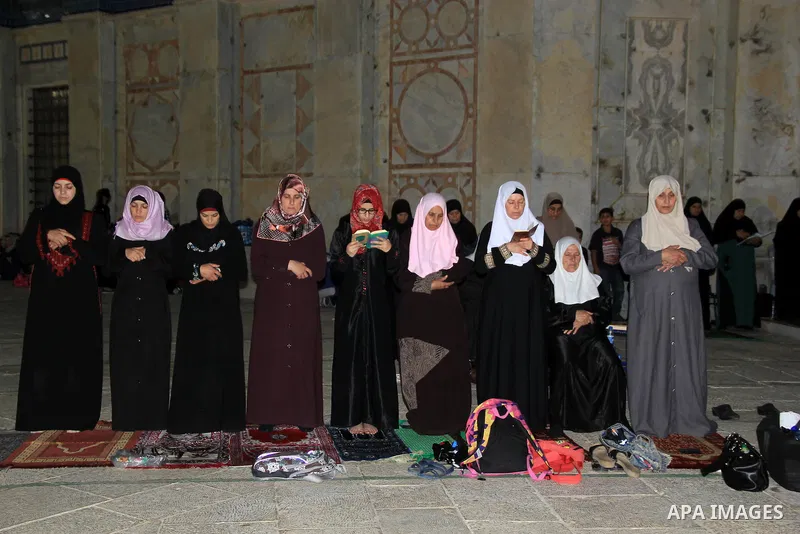 Palestinian women perform "Taraweeh", nightly prayer of the month of Ramadan, in front of the Dome of the Rock mosque, in Jerusalem's old city on June 14, 2016. Ramadan is sacred to Muslims because it is during that mont...