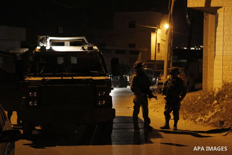 Israeli army soldiers stand guard during a searching and arresting in the West Bank village of Yatta June 15 2016. the Israeli army carry on a night after night military campaign in Yatta after 2 Palestinians attacked an...