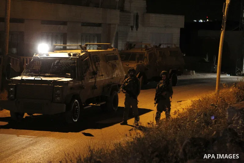 Israeli army soldiers stand guard during a searching and arresting in the West Bank village of Yatta June 15 2016. the Israeli army carry on a night after night military campaign in Yatta after 2 Palestinians attacked an...