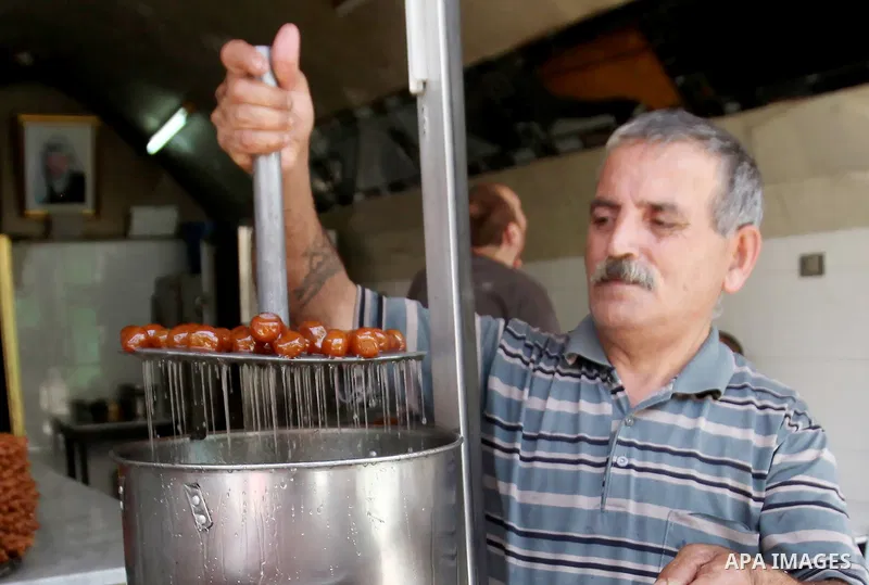 A Palestinian vendor prepares traditional sweets called "awwamah" at his shop at a market during the holy month of Ramadan in the West Bank city of Nablus, on June 15, 2016. Ramadan is sacred to Muslims because it is dur...