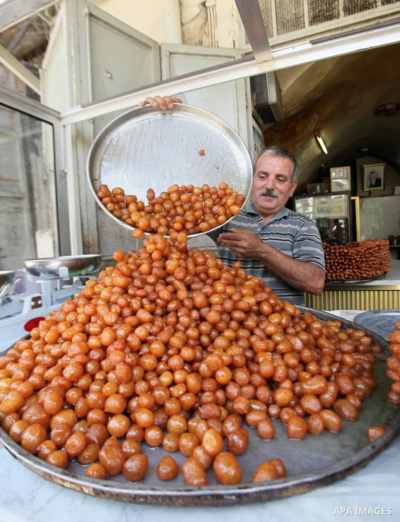 A Palestinian vendor prepares traditional sweets called "awwamah" at his shop at a market during the holy month of Ramadan in the West Bank city of Nablus, on June 15, 2016. Ramadan is sacred to Muslims because it is dur...