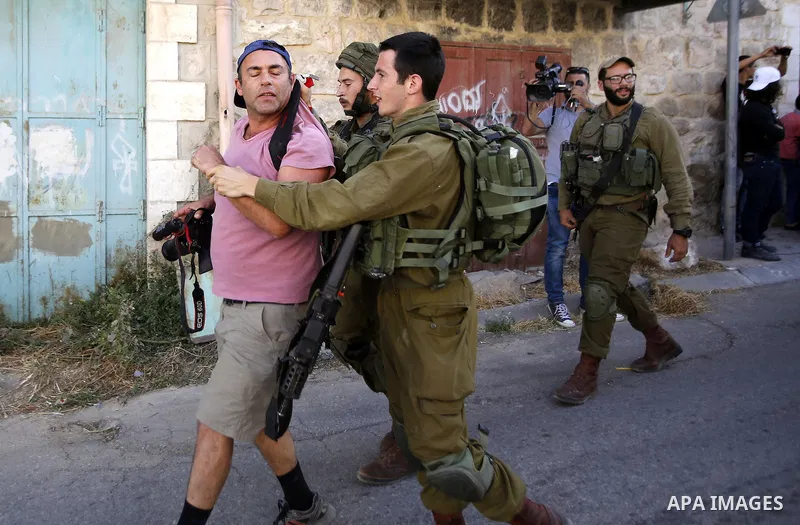 Israeli soldiers detain a demonstrator after a protest against the closure of a route used by Palestinians to pass to a school and houses in Shuhada street, in the West Bank city of Hebron, June 15, 2016. Photo by Wisam...