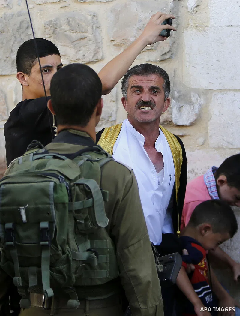 A Palestinian man shouts at Israeli troops after his son was pushed following a protest against the closure of a route used by Palestinians to pass to a school and houses in Shuhada street, in the West Bank city of Hebro...