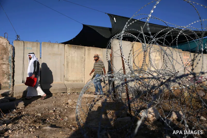 Palestinian men walk past Qalandia checkpoint between the West Bank city of Ramallah and Jerusalem on June 17, 2016, as they head to Jerusalem's Al-Aqsa mosque for the second Friday prayer of the holy Muslim fasting mont...