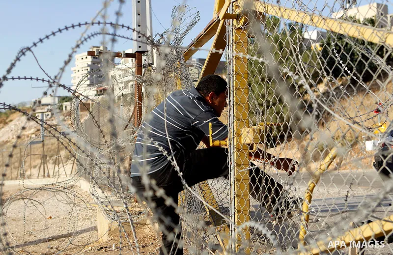 Palestinians, not permitted by Israeli security forces to cross into Jerusalem from the West Bank due to an age limit, climb an Israeli fence between the West Bank town of Bethlehem and Jerusalem as they try to make thei...