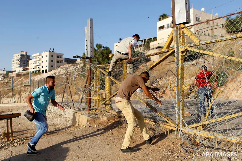 Palestinians, not permitted by Israeli security forces to cross into Jerusalem from the West Bank due to an age limit, climb an Israeli fence between the West Bank town of Bethlehem and Jerusalem as they try to make thei...