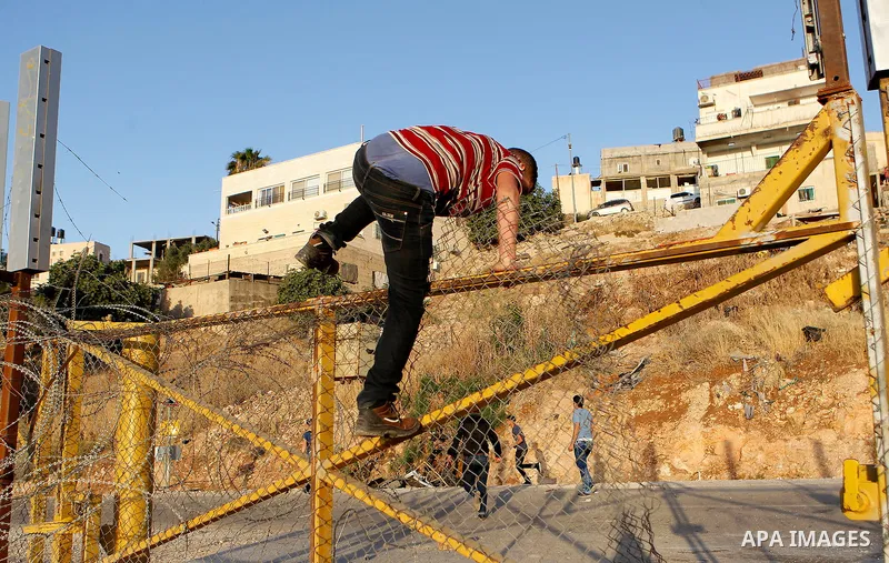 Palestinians, not permitted by Israeli security forces to cross into Jerusalem from the West Bank due to an age limit, climb an Israeli fence between the West Bank town of Bethlehem and Jerusalem as they try to make thei...