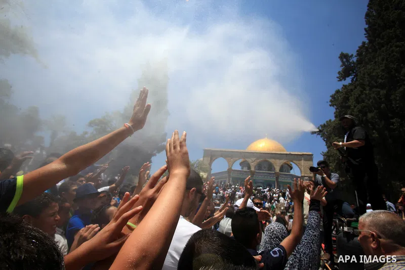 Palestinian Muslim worshippers are sprayed with water to cool down after prayers outside the Dome of the Rock mosque at the al-Aqsa mosque compound in Jerusalem's old city on June 17, 2016 during the holy fasting month o...