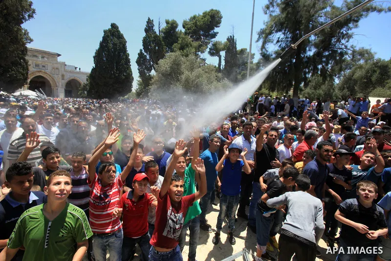 Palestinian Muslim worshippers are sprayed with water to cool down after prayers outside the Dome of the Rock mosque at the al-Aqsa mosque compound in Jerusalem's old city on June 17, 2016 during the holy fasting month o...