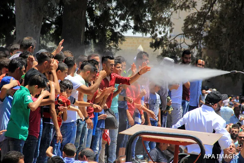 Palestinian Muslim worshippers are sprayed with water to cool down after prayers outside the Dome of the Rock mosque at the al-Aqsa mosque compound in Jerusalem's old city on June 17, 2016 during the holy fasting month o...