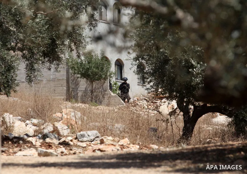 A member of Israeli security forces aims his weapon at Palestinian protesters during clashes following a demonstration against the expropriation of Palestinian land by Israel, on June 17, 2016 in the village of Kfar Qadd...