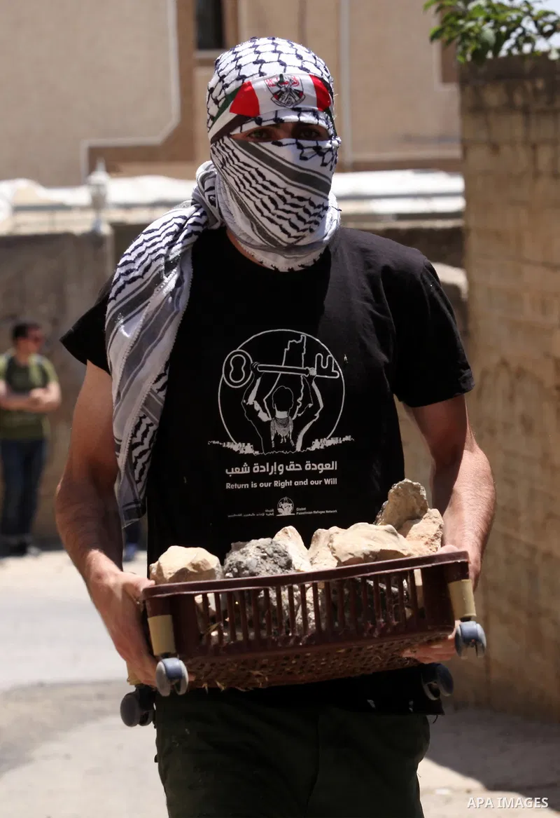 A Palestinian protester carries stones during clashes with Israeli security forces following a demonstration against the expropriation of Palestinian land by Israel, on June 17, 2016 in the village of Kfar Qaddum, near N...