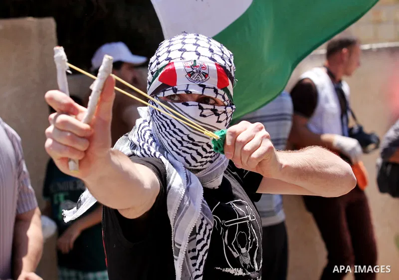A Palestinian protester uses a slingshot to throw stones towards Israeli security forces during clashes following a demonstration against the expropriation of Palestinian land by Israel, on June 17, 2016 in the village o...