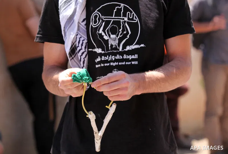 A Palestinian protester uses a slingshot to throw stones towards Israeli security forces during clashes following a demonstration against the expropriation of Palestinian land by Israel, on June 17, 2016 in the village o...
