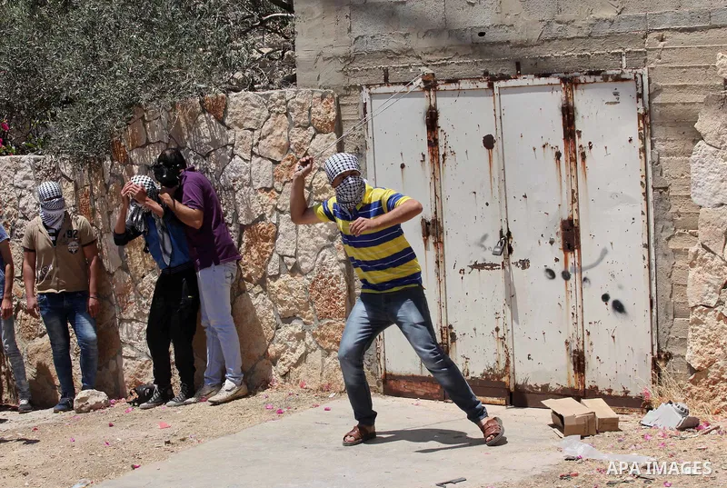 A Palestinian protester uses a slingshot to throw stones towards Israeli security forces during clashes following a demonstration against the expropriation of Palestinian land by Israel, on June 17, 2016 in the village o...