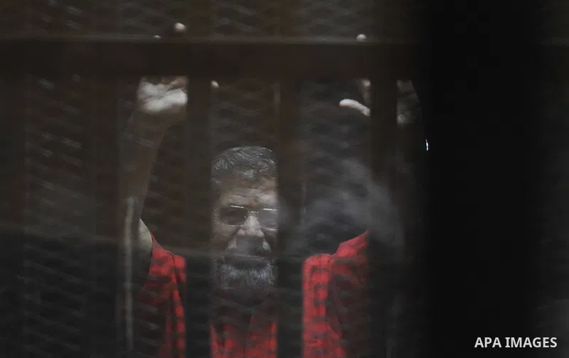 Egypt's ousted Islamist president Mohamed Morsi, wearing a red uniform, looks on from behind the defendant's bars during his trial on espionage charges at a court in Cairo on June 18, 2016. An Egyptian court sentenced Mo...