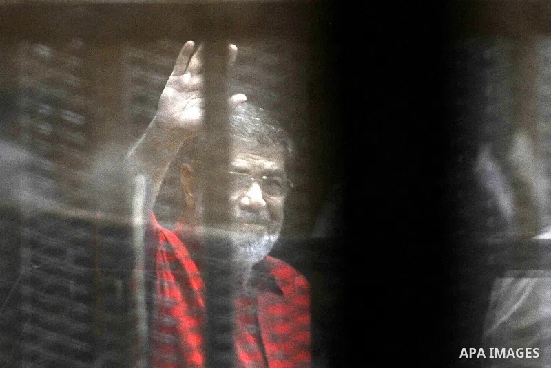 Egypt's ousted Islamist president Mohamed Morsi, wearing a red uniform, looks on from behind the defendant's bars during his trial on espionage charges at a court in Cairo on June 18, 2016. An Egyptian court sentenced Mo...