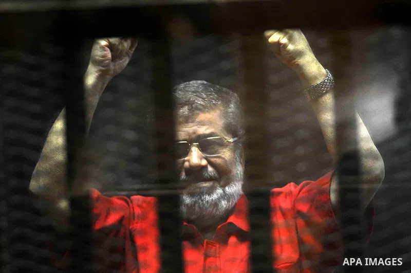 Egypt's ousted Islamist president Mohamed Morsi, wearing a red uniform, looks on from behind the defendant's bars during his trial on espionage charges at a court in Cairo on June 18, 2016. An Egyptian court sentenced Mo...