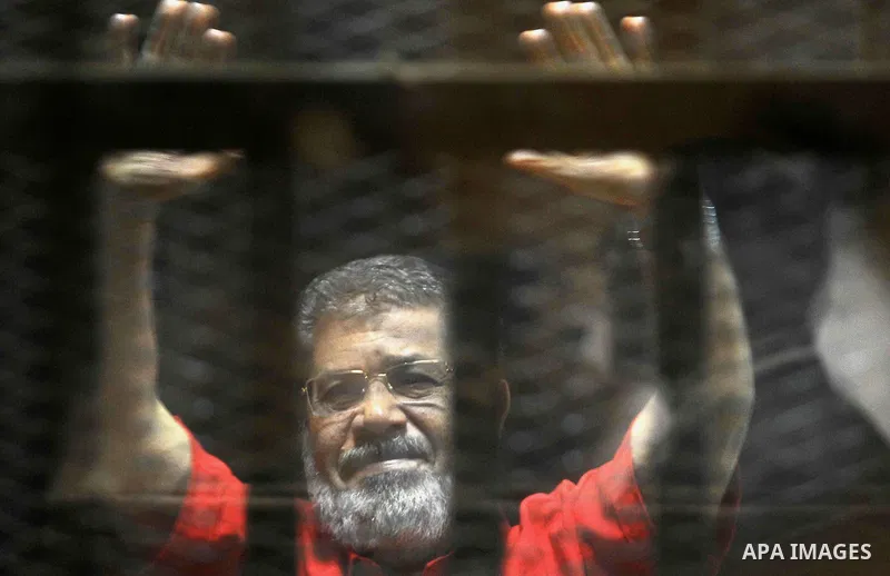 Egypt's ousted Islamist president Mohamed Morsi, wearing a red uniform, looks on from behind the defendant's bars during his trial on espionage charges at a court in Cairo on June 18, 2016. An Egyptian court sentenced Mo...