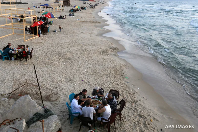 Palestinian Muslims eat their Iftar meal as they break their fast during the holy fasting month of Ramadan at the beach of the Mediterranean sea on the coast of Gaza city on June 18, 2016. Photo by Yasser Qudih