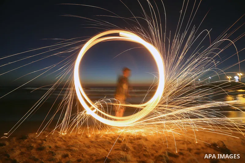 A Palestinian boy plays with fire crackers during the holy fasting month of Ramadan at the beach of the Mediterranean sea on the coast of Gaza city on June 18, 2016. Photo by Yasser Qudih