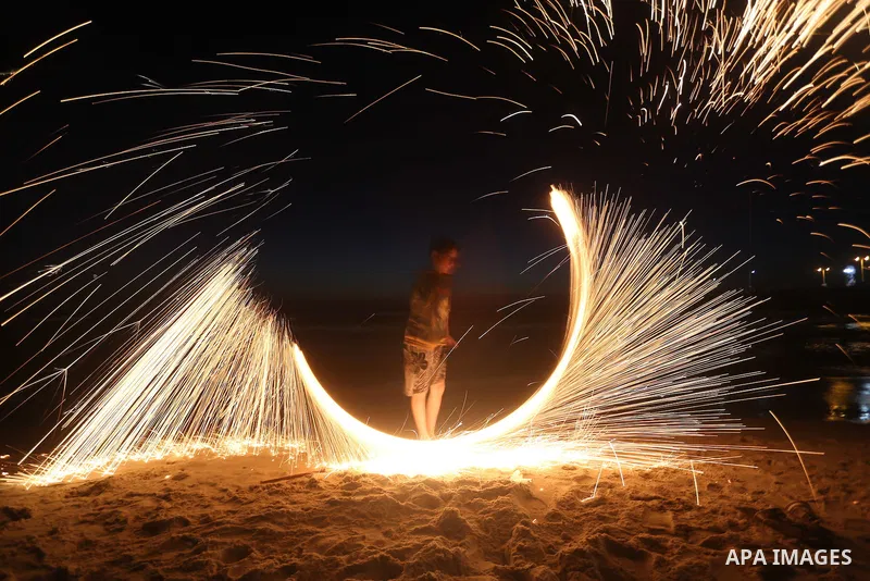 A Palestinian boy plays with fire crackers during the holy fasting month of Ramadan at the beach of the Mediterranean sea on the coast of Gaza city on June 18, 2016. Photo by Yasser Qudih