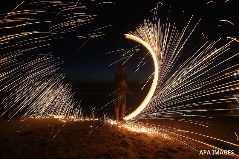 A Palestinian boy plays with fire crackers during the holy fasting month of Ramadan at the beach of the Mediterranean sea on the coast of Gaza city on June 18, 2016. Photo by Yasser Qudih