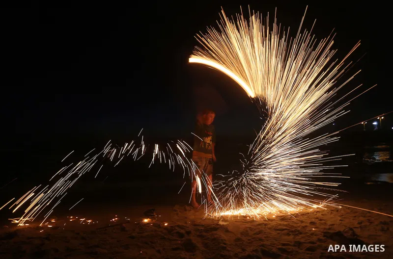 A Palestinian boy plays with fire crackers during the holy fasting month of Ramadan at the beach of the Mediterranean sea on the coast of Gaza city on June 18, 2016. Photo by Yasser Qudih