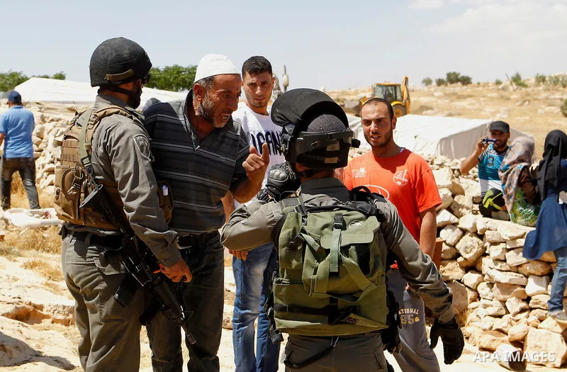 A Palestinian man scuffles with an Israeli border policeman as Israeli troops demolish sheds belonging to Palestinians near the West Bank village of Yatta, south of Hebron June 19, 2016. Photo by Wisam Hashlamoun