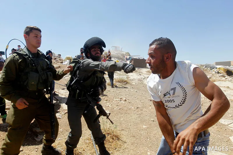 A Palestinian man scuffles with an Israeli border policeman as Israeli troops demolish sheds belonging to Palestinians near the West Bank village of Yatta, south of Hebron June 19, 2016. Photo by Wisam Hashlamoun