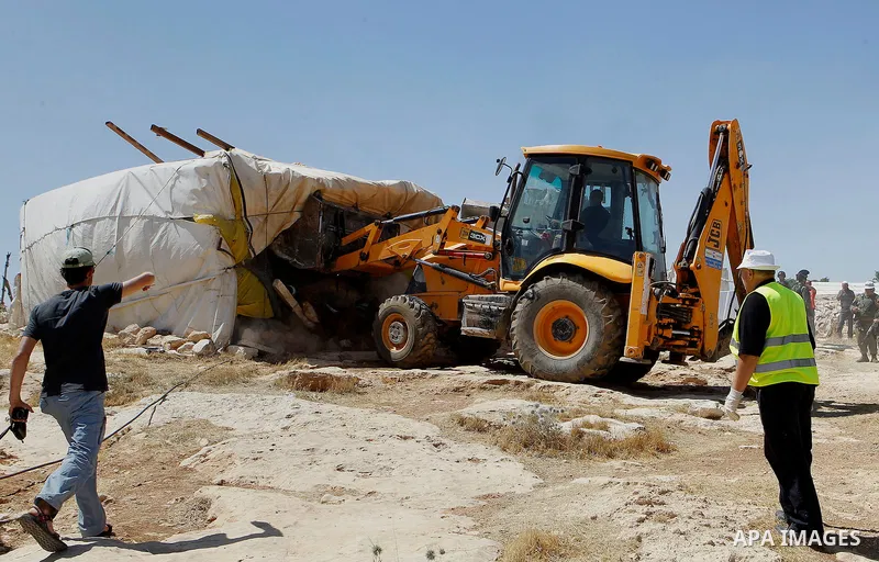 An Israeli bulldozer demolishes sheds belonging to Palestinians near the West Bank village of Yatta, south of Hebron June 19, 2016. Photo by Wisam Hashlamoun