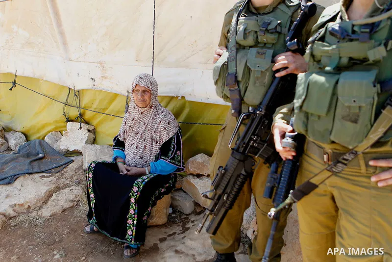 An old Palestinian woman sits next her shed as Israeli troops demolish sheds belonging to Palestinians near the West Bank village of Yatta, south of Hebron June 19, 2016. Photo by Wisam Hashlamoun