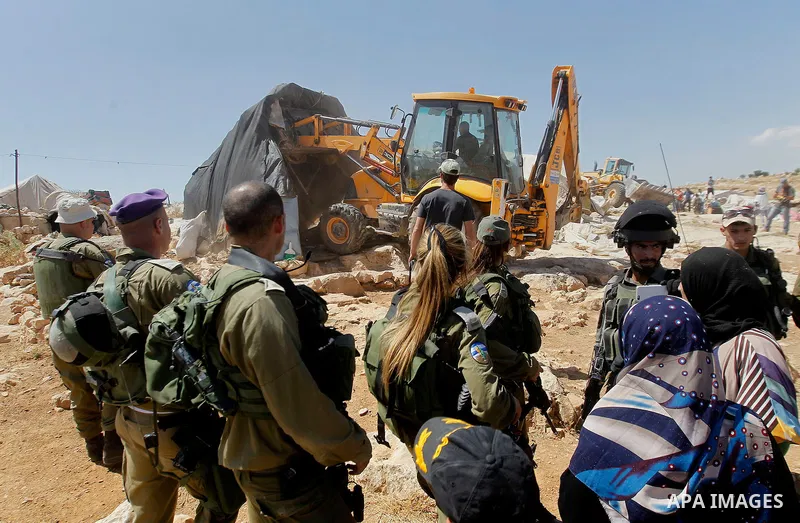 Israeli soldiers stand guard as Israeli troops demolish sheds belonging to Palestinians near the West Bank village of Yatta, south of Hebron June 19, 2016. Photo by Wisam Hashlamoun
