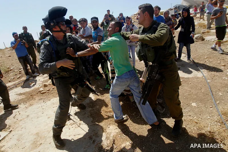 A Palestinian man scuffles with an Israeli border policeman as Israeli troops demolish sheds belonging to Palestinians near the West Bank village of Yatta, south of Hebron June 19, 2016. Photo by Wisam Hashlamoun