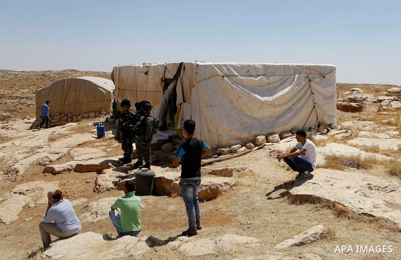 Palestinian look on as Israeli troops demolish sheds belonging to Palestinians near the West Bank village of Yatta, south of Hebron June 19, 2016. Photo by Wisam Hashlamoun