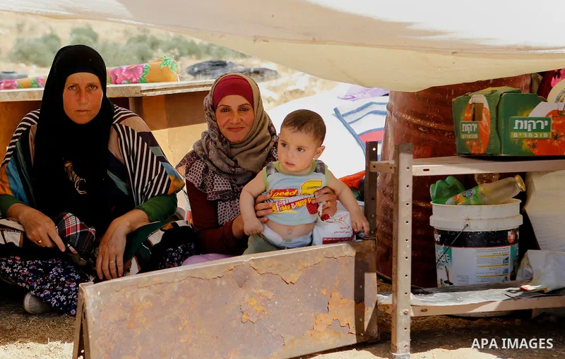 Palestinian women look on as Israeli troops demolish sheds belonging to Palestinians near the West Bank village of Yatta, south of Hebron June 19, 2016. Photo by Wisam Hashlamoun