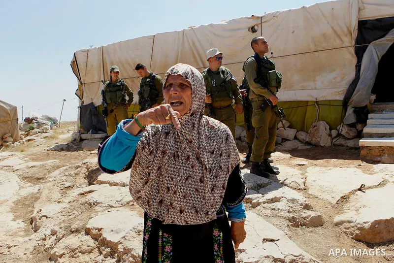 An old Palestinian woman reacts as Israeli troops demolish sheds belonging to Palestinians near the West Bank village of Yatta, south of Hebron June 19, 2016. Photo by Wisam Hashlamoun